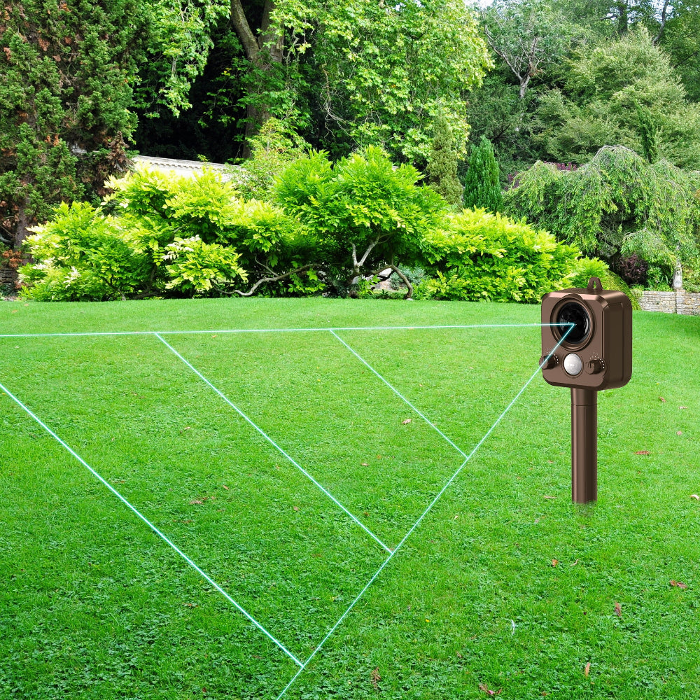 Outdoor scene with a laser level device on grass, surrounded by greenery.