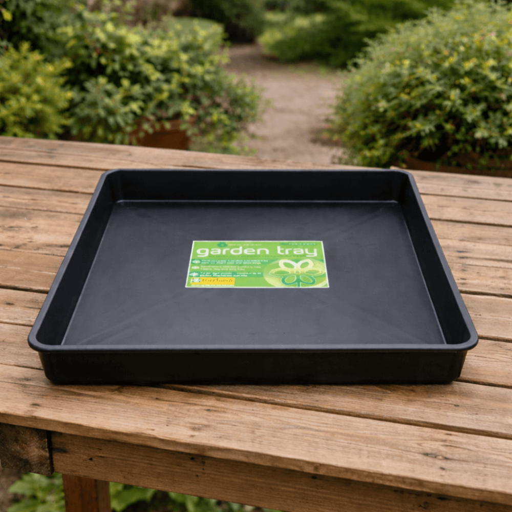 Black garden tray with 'garden tray' label on a wooden surface with greenery in the background