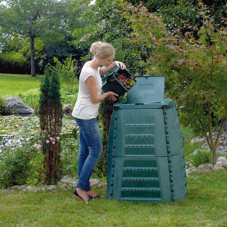 A Lady putting her food scraps into a large green thermo star composter