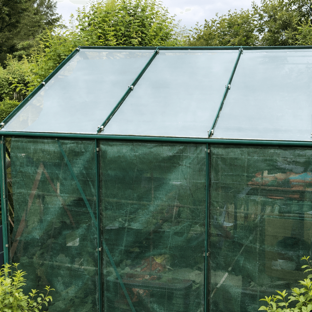 Green greenhouse with mesh cover in a garden setting
