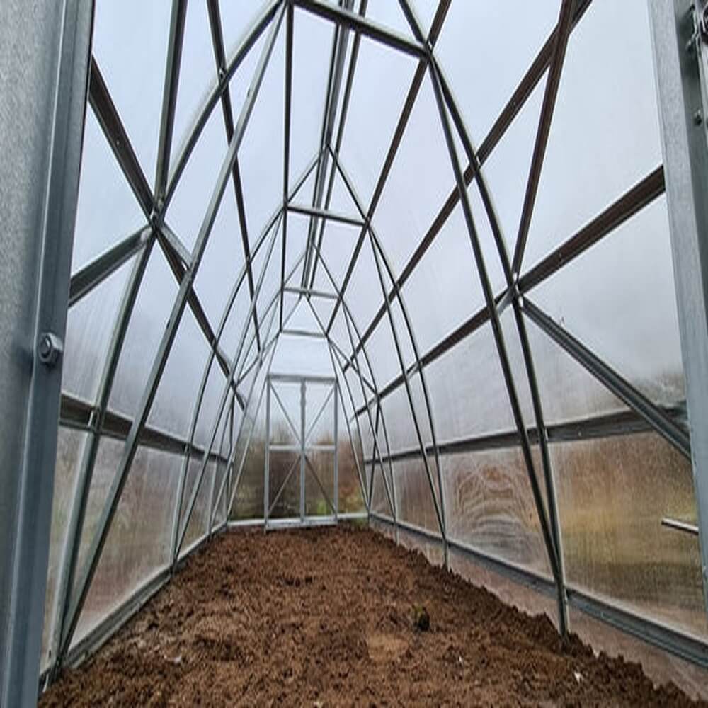 Interior of a greenhouse with metal frame and soil floor