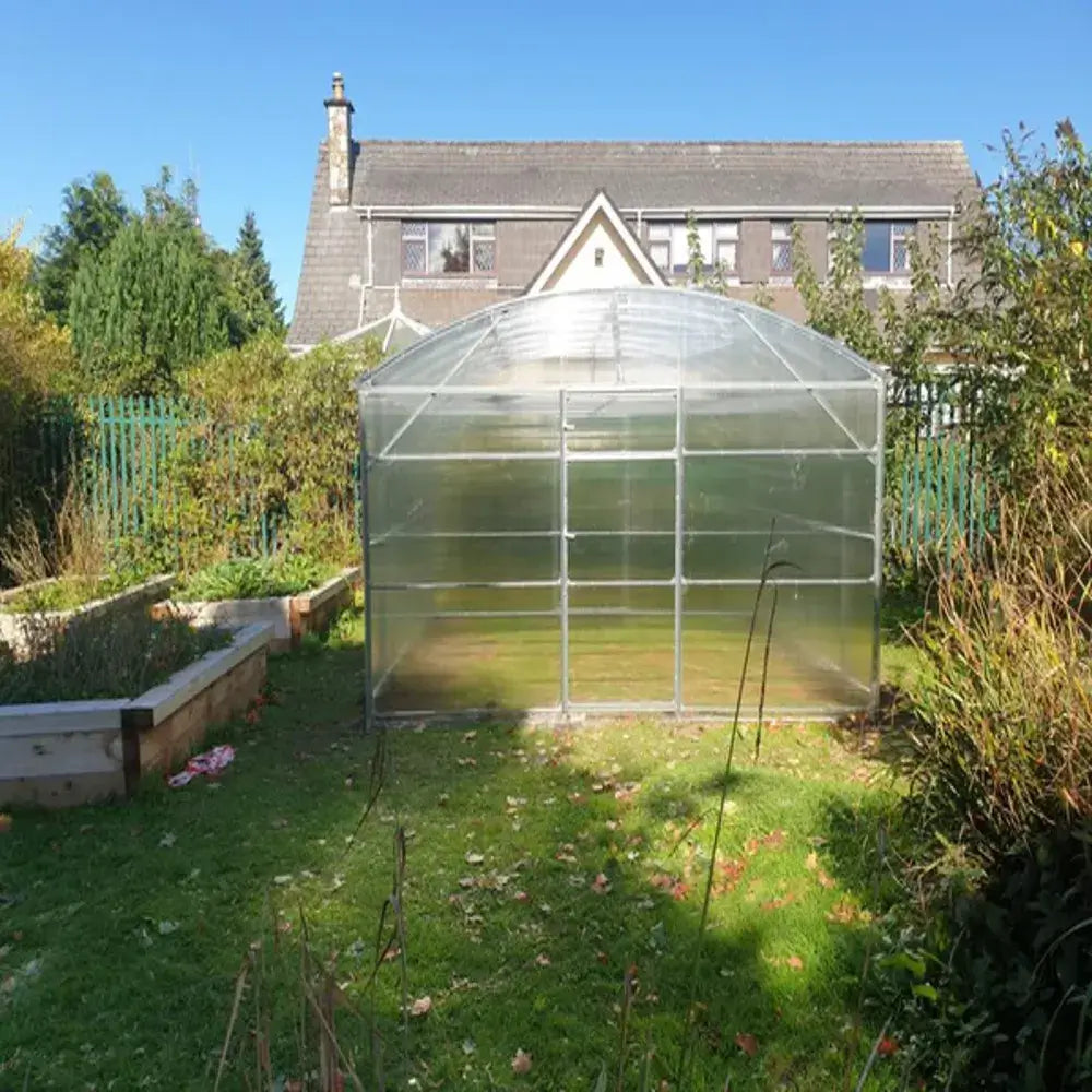 Greenhouse in a garden with a house in the background