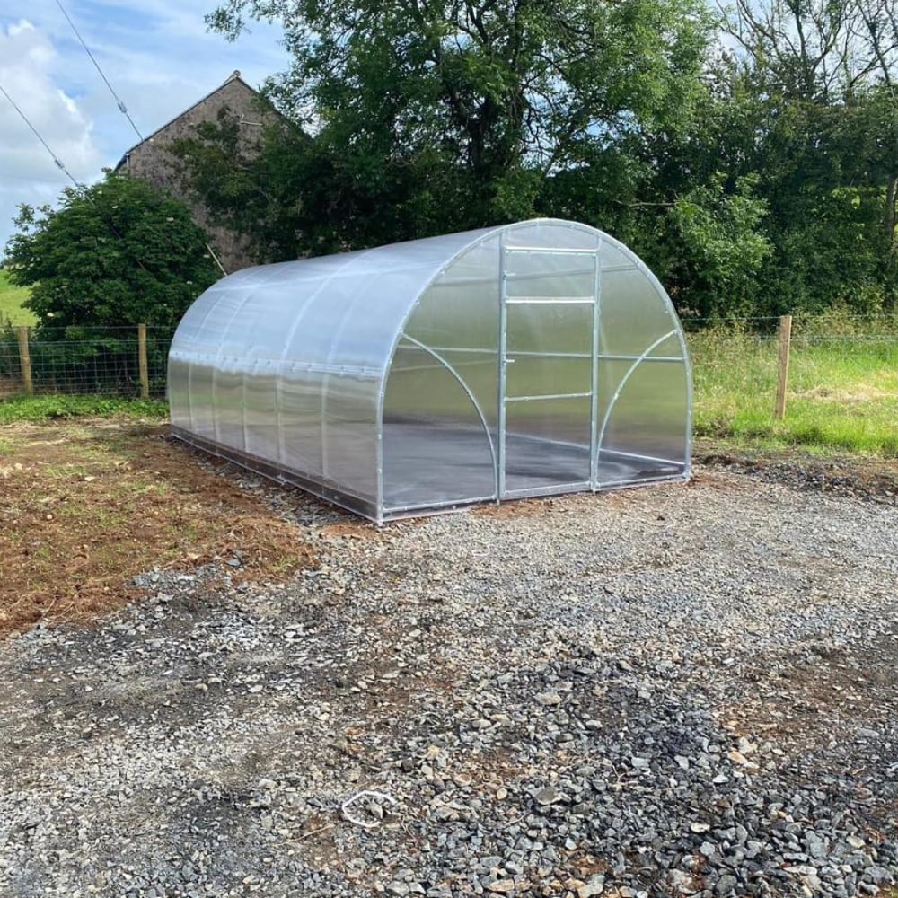 A polytunnel greenhouse with a metal frame and clear polycarbonate covering