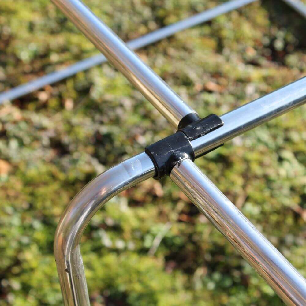 Close-up of a portable garden cage with a black clip against a blurred green background