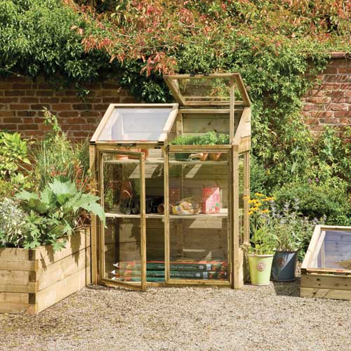 A wooden small greenhouse in a beautiful garden