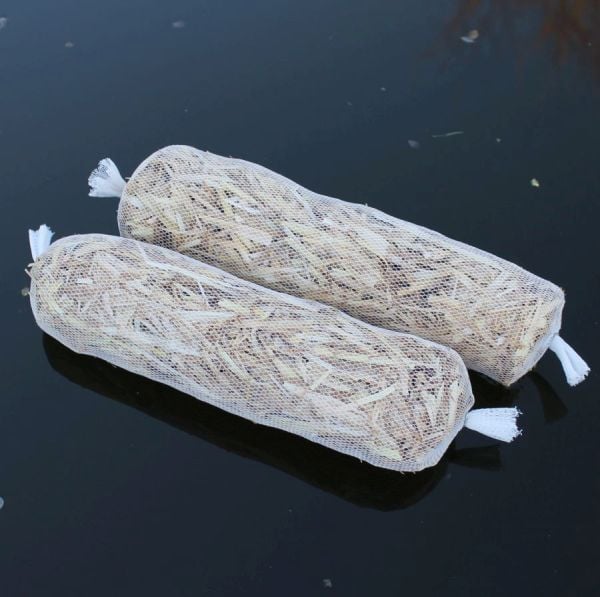 barley straw bags sitting on pond
