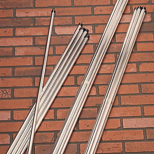 A collection of aluminum plant support stakes with black ground spikes, laid out in front of a brick wall.