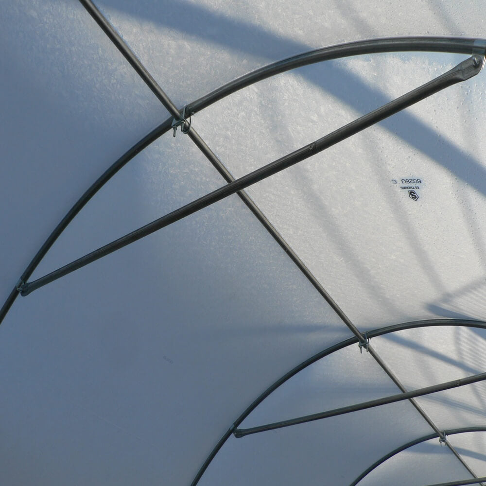 Close-up of a transparent canopy with metal frames against a blue sky.