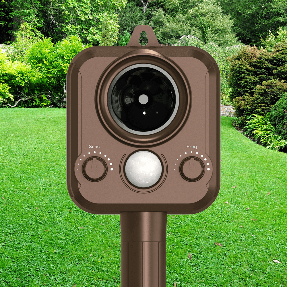 Brown outdoor security camera on a green lawn with trees in the background