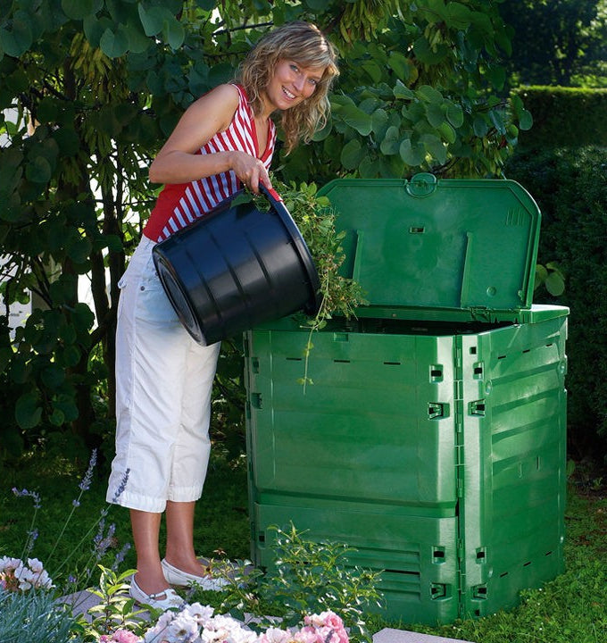 Lady pouring her grass scraps into a green composter bin