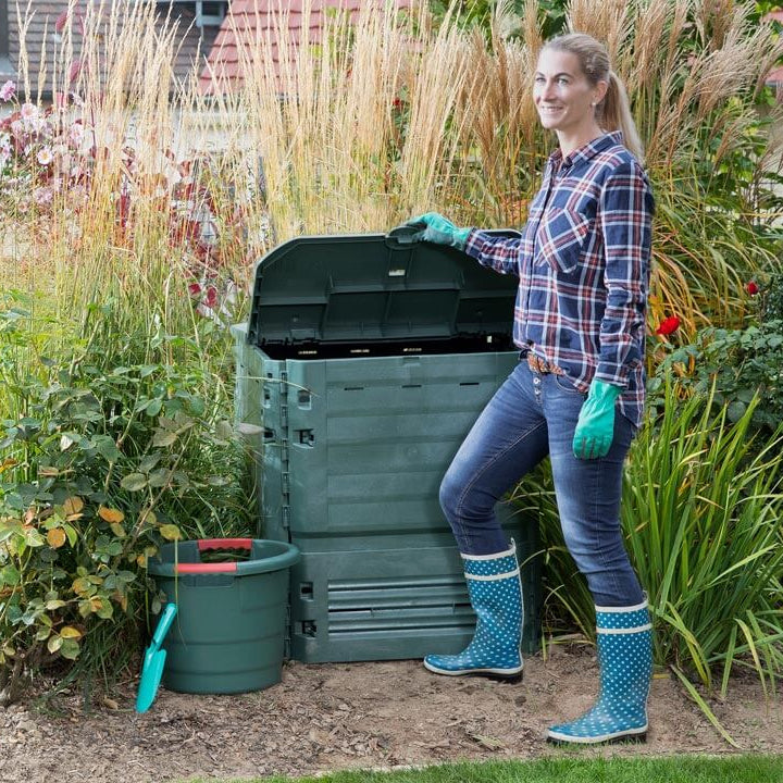 A Lady opening large green composter in the garden