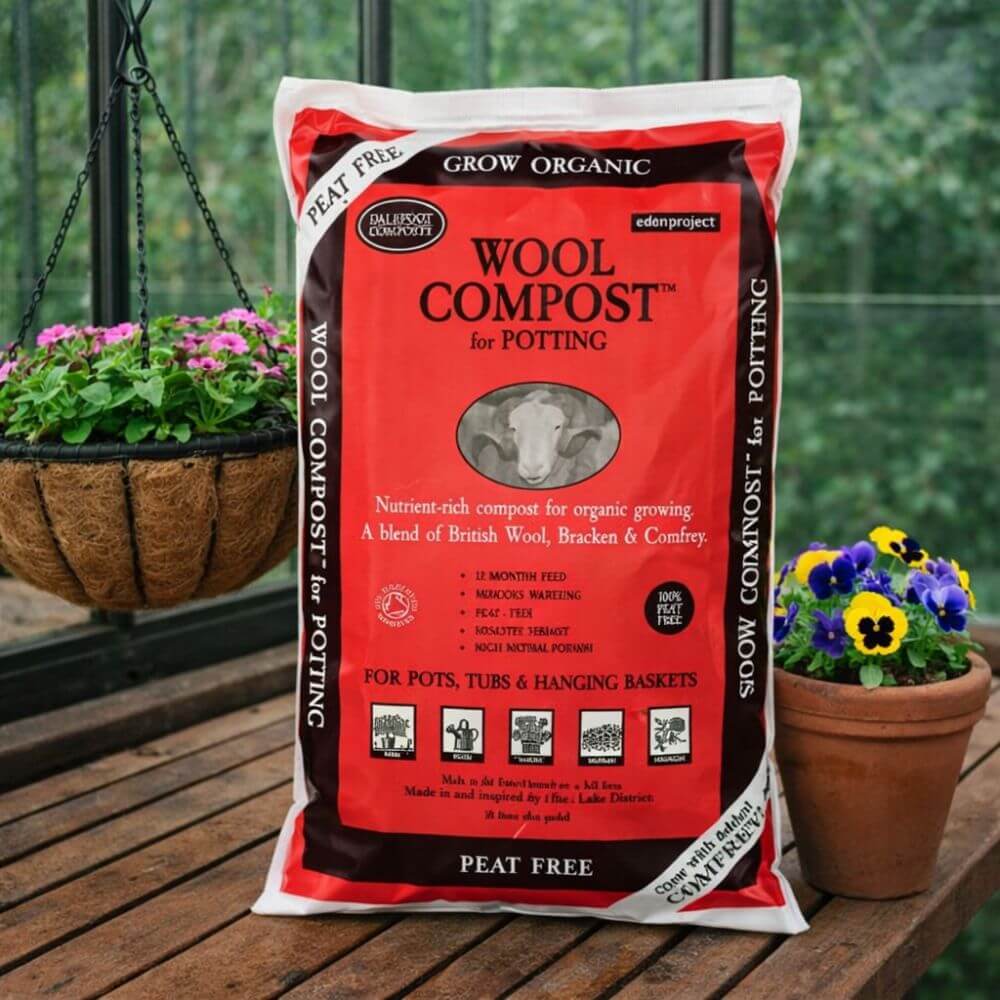 Bag of Wool Compost for Potting on a wooden surface with potted plants in the background.
