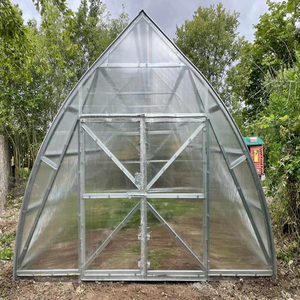 Clear glass greenhouse with metal frame in a natural setting