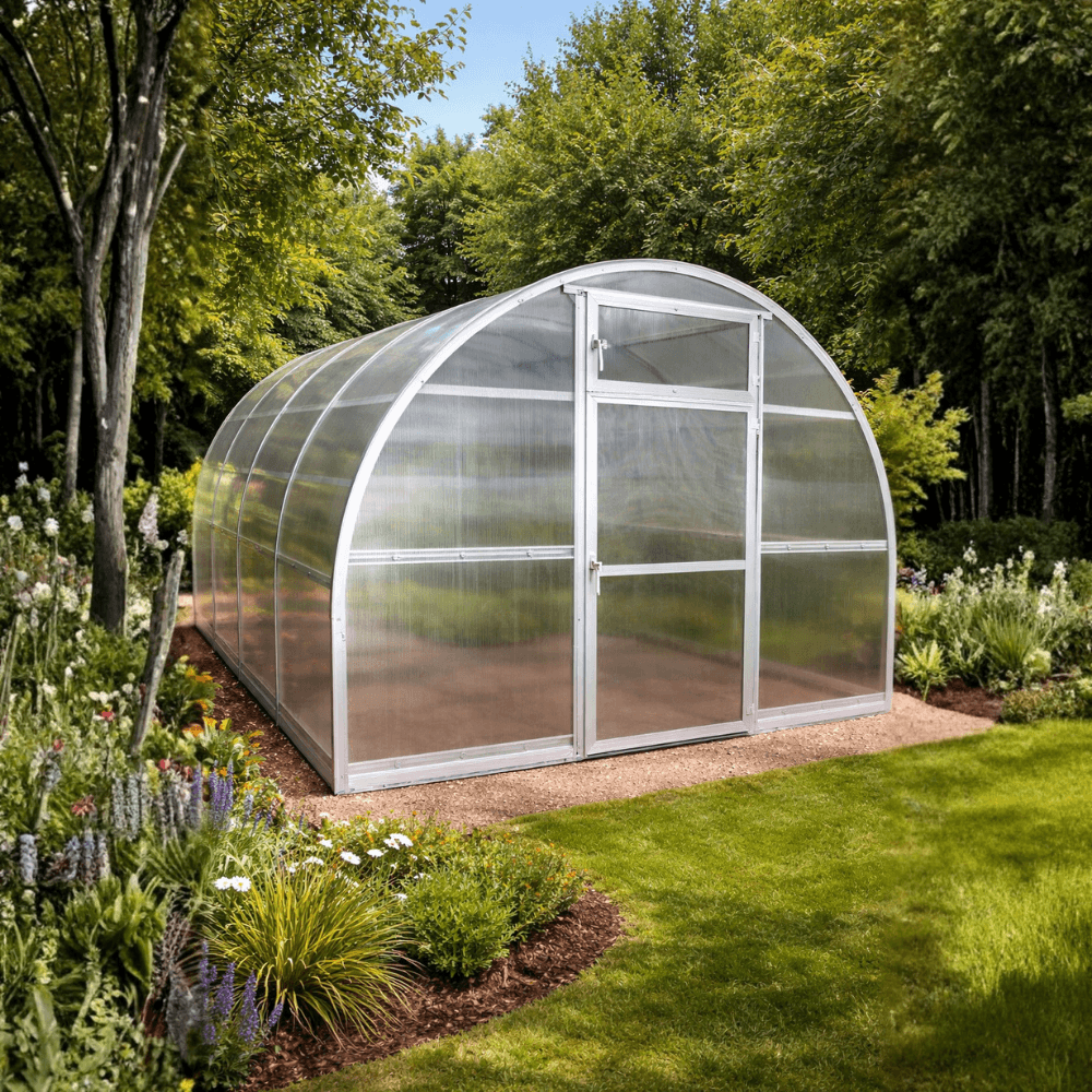 Polycarbonate greenhouse in a garden setting with trees and flowers.
