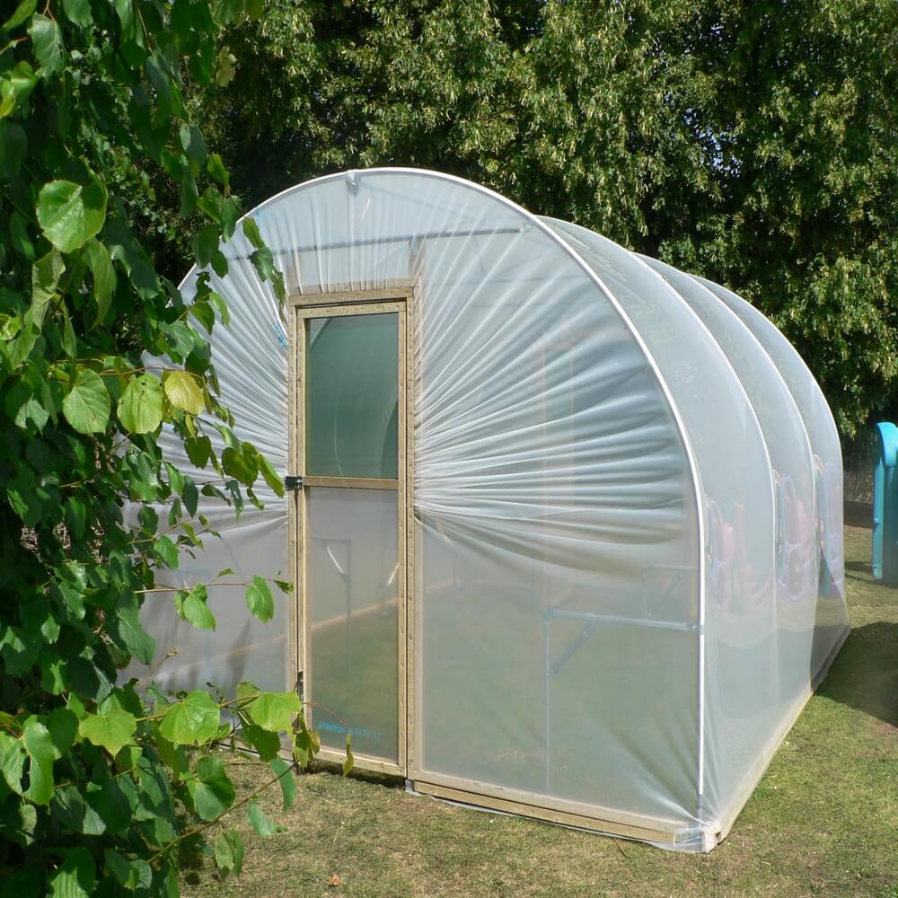 Polytunnel with transparent covering in a garden setting